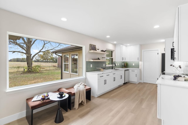 kitchen featuring sink, white cabinetry, decorative backsplash, stainless steel dishwasher, and light wood-type flooring