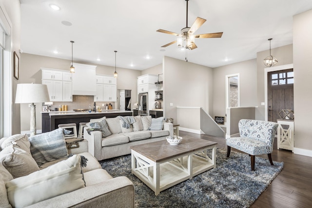 living room with dark wood-type flooring and ceiling fan with notable chandelier