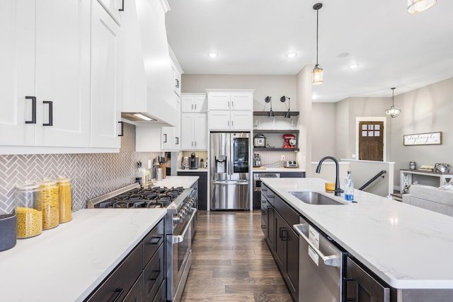 kitchen featuring decorative light fixtures, sink, white cabinets, stainless steel appliances, and custom range hood