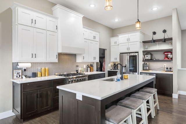 kitchen with white cabinets, an island with sink, sink, and stainless steel fridge