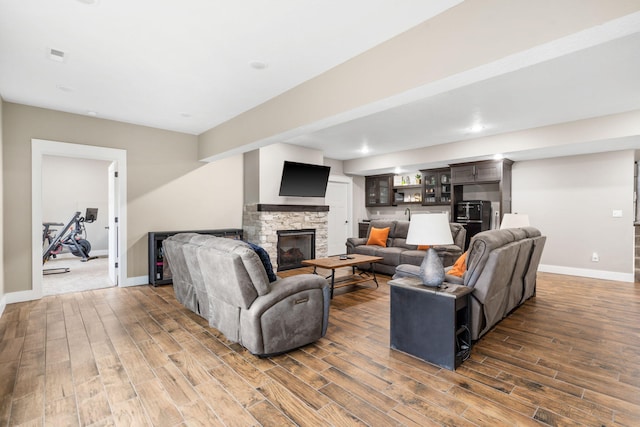 living room featuring dark hardwood / wood-style floors and a stone fireplace