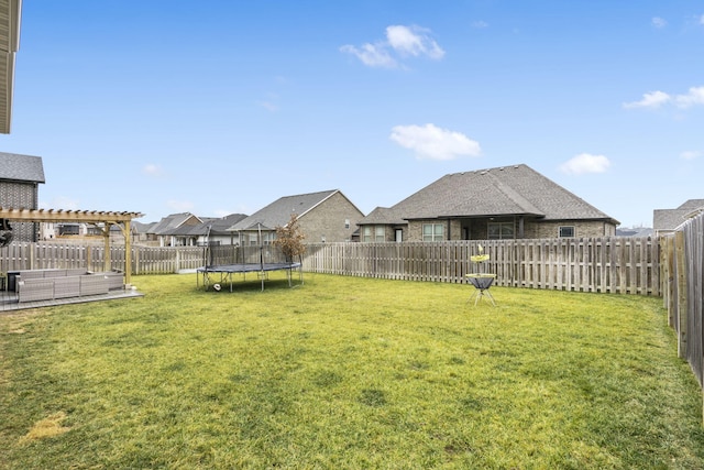 view of yard with a trampoline and a pergola