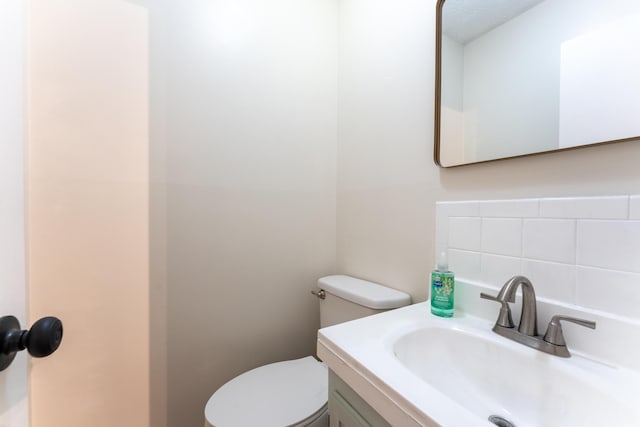 bathroom featuring vanity, backsplash, and toilet