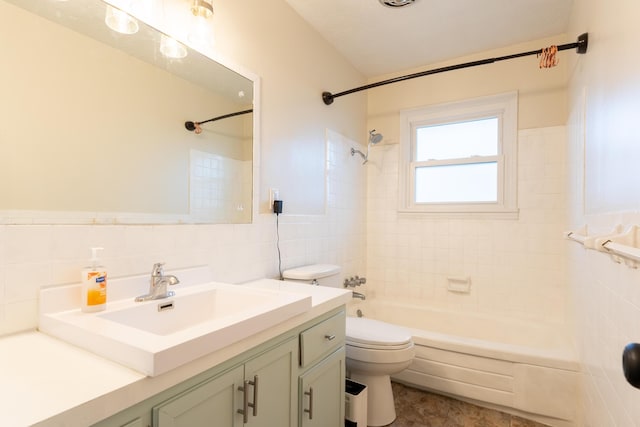 full bathroom featuring vanity, tiled shower / bath, tile walls, and toilet