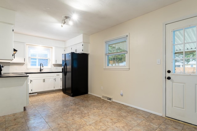 kitchen featuring sink, backsplash, white cabinets, range, and black fridge with ice dispenser