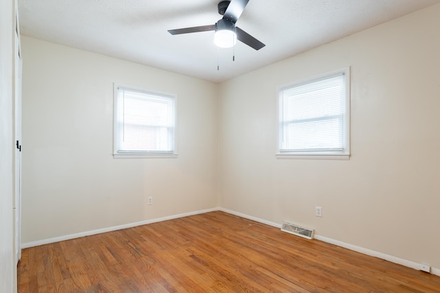 spare room with ceiling fan, plenty of natural light, and wood-type flooring