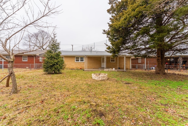 rear view of property featuring a yard and a fire pit