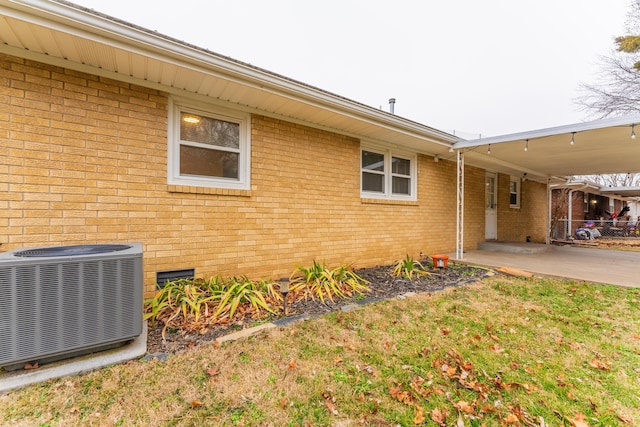 exterior space featuring a carport, a lawn, and central air condition unit