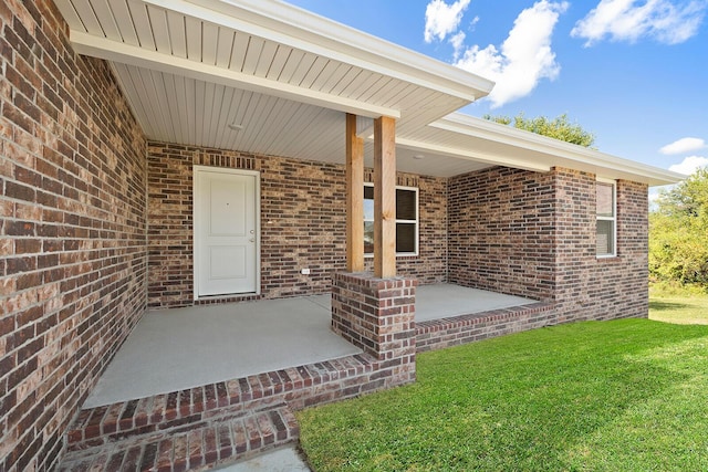 view of exterior entry with a yard and a patio area