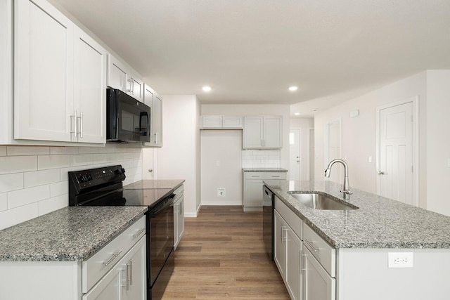 kitchen featuring white cabinetry, an island with sink, sink, and black appliances