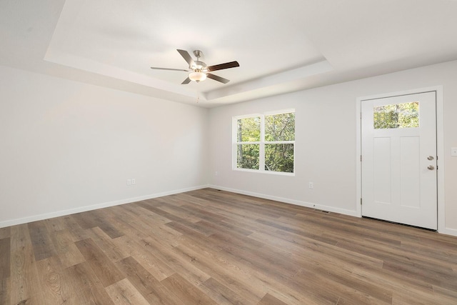 entrance foyer with ceiling fan, wood-type flooring, and a tray ceiling