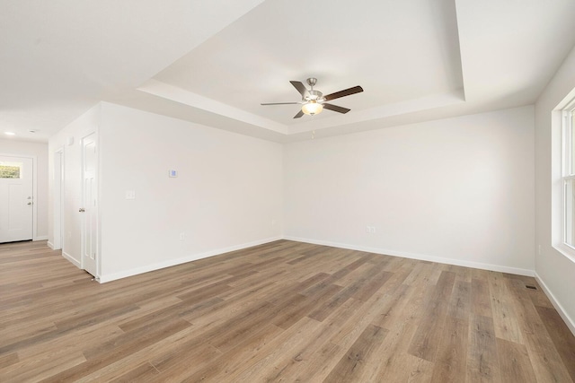 spare room with a tray ceiling, light hardwood / wood-style flooring, and a wealth of natural light