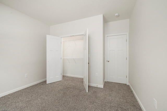 unfurnished bedroom featuring a walk in closet, light colored carpet, and a closet