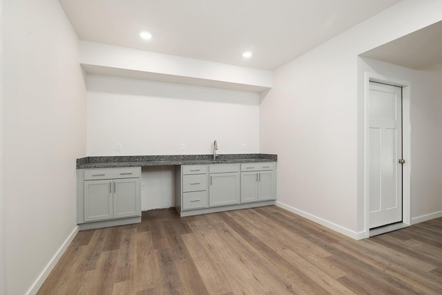 bar with hardwood / wood-style flooring, sink, and gray cabinetry