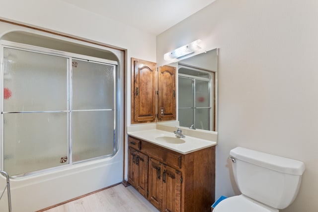 full bathroom featuring toilet, vanity, bath / shower combo with glass door, and hardwood / wood-style floors