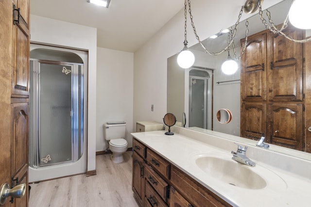 bathroom featuring hardwood / wood-style flooring, vanity, toilet, and a shower with shower door