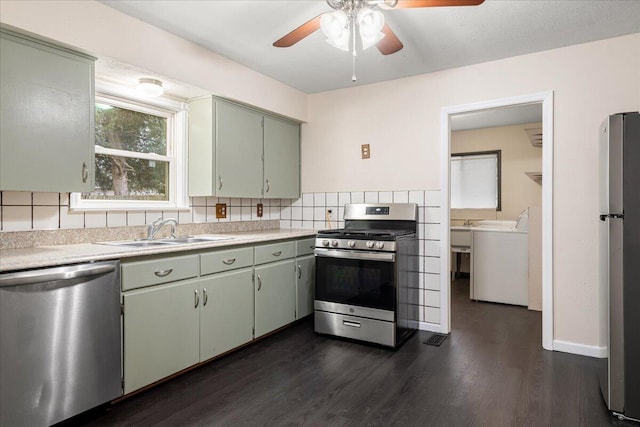 kitchen with sink, backsplash, stainless steel appliances, dark hardwood / wood-style floors, and washer / dryer