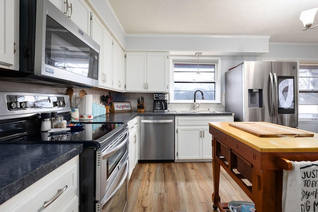 kitchen with sink, crown molding, appliances with stainless steel finishes, white cabinetry, and plenty of natural light