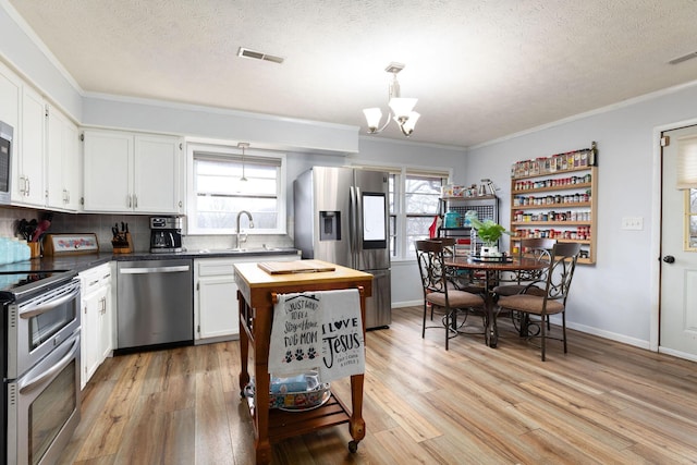 kitchen featuring sink, light hardwood / wood-style flooring, appliances with stainless steel finishes, white cabinetry, and backsplash