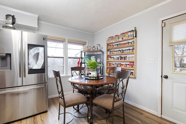 dining space featuring ornamental molding, plenty of natural light, and light hardwood / wood-style floors