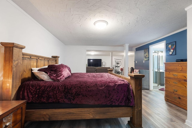 bedroom with wood-type flooring, crown molding, and a textured ceiling