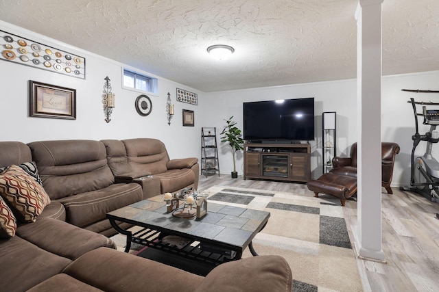 living room featuring ornamental molding, a textured ceiling, and light wood-type flooring