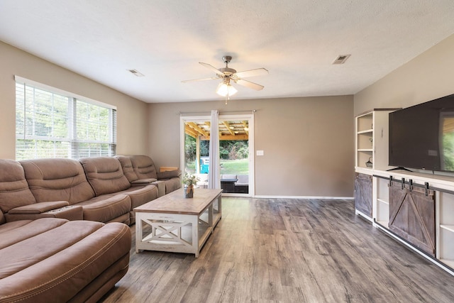 130 A St, Taneyville, MO 65759 - living room featuring ceiling fan, a healthy amount of sunlight, wood-type flooring, and a textured ceiling