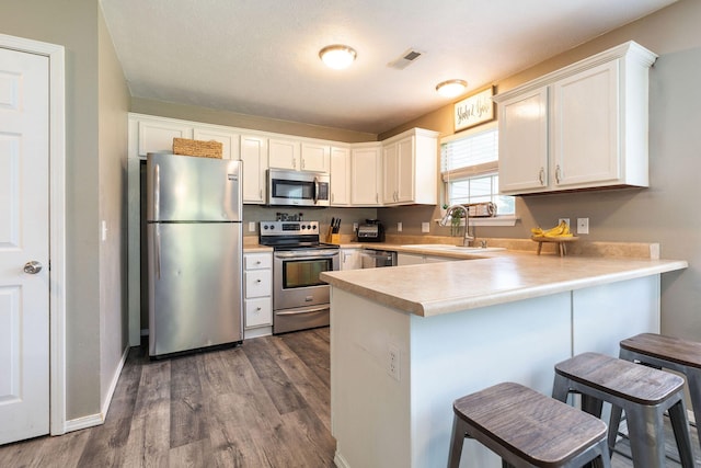 130 A St, Taneyville, MO 65759 - kitchen with sink, white cabinetry, appliances with stainless steel finishes, a kitchen breakfast bar, and kitchen peninsula