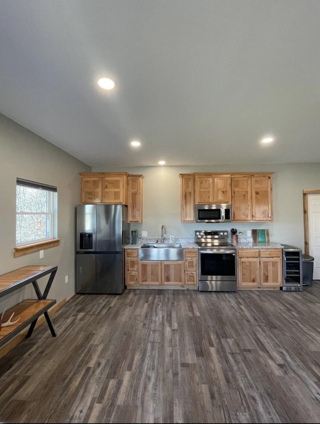 kitchen with dark wood-type flooring, sink, light stone counters, stainless steel appliances, and beverage cooler