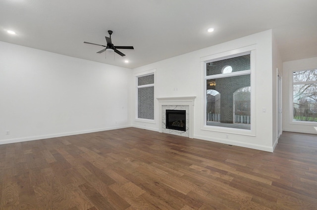 unfurnished living room with dark wood-type flooring, ceiling fan, and a premium fireplace