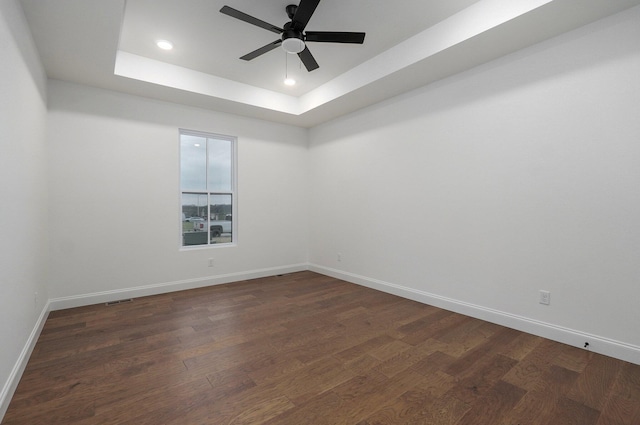 empty room featuring ceiling fan, dark hardwood / wood-style floors, and a raised ceiling