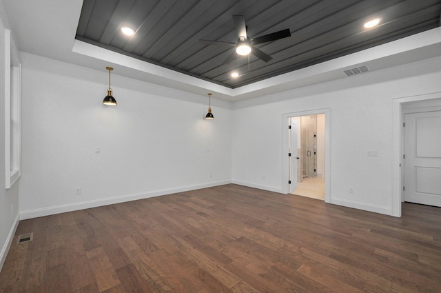 spare room featuring ceiling fan, a tray ceiling, and dark hardwood / wood-style flooring