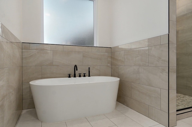 bathroom featuring a bath and tile walls