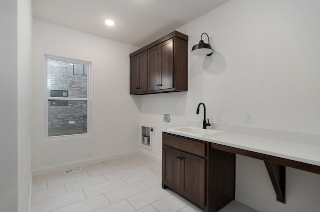 washroom featuring hookup for a washing machine, sink, hookup for an electric dryer, and cabinets