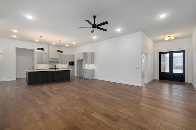 kitchen featuring french doors, sink, hanging light fixtures, a center island with sink, and dark hardwood / wood-style flooring