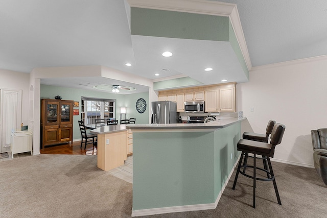 kitchen with a breakfast bar, light carpet, kitchen peninsula, a kitchen island, and stainless steel appliances