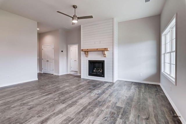 unfurnished living room featuring ceiling fan, a large fireplace, and dark hardwood / wood-style flooring