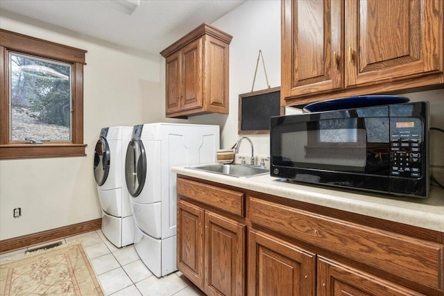 laundry room featuring light tile patterned flooring, cabinets, sink, and washing machine and dryer
