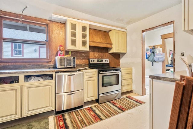 kitchen with premium range hood, appliances with stainless steel finishes, cream cabinets, and decorative backsplash