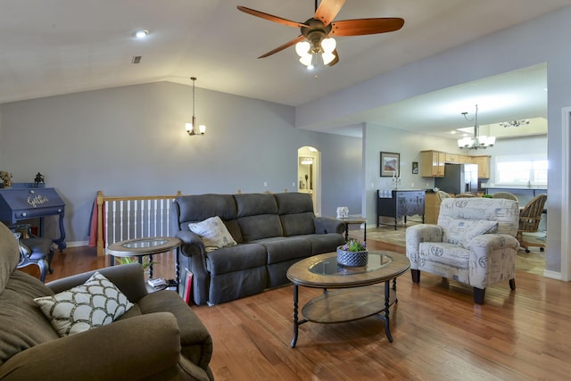 living room with lofted ceiling, ceiling fan with notable chandelier, and light hardwood / wood-style floors