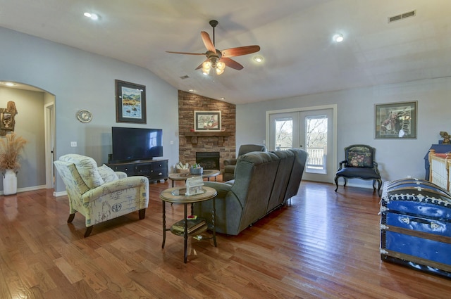 living room featuring lofted ceiling, ceiling fan, hardwood / wood-style floors, a stone fireplace, and french doors