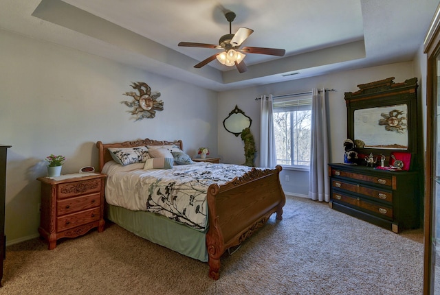 carpeted bedroom featuring a raised ceiling and ceiling fan