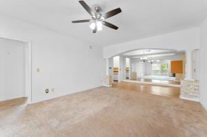 unfurnished living room with carpet floors and ceiling fan with notable chandelier