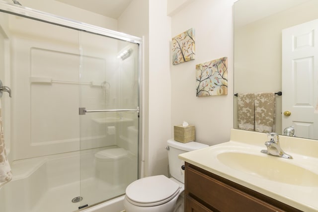 bathroom featuring a shower with door, vanity, and toilet