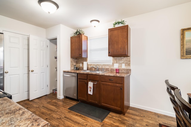 kitchen with dark wood-type flooring, stainless steel dishwasher, sink, and decorative backsplash