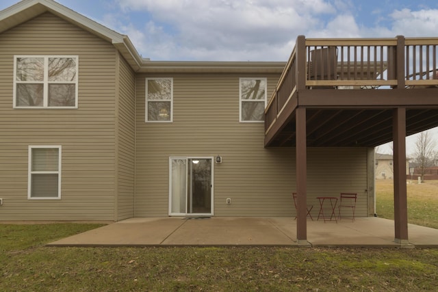 back of property with a wooden deck, a patio, and a lawn