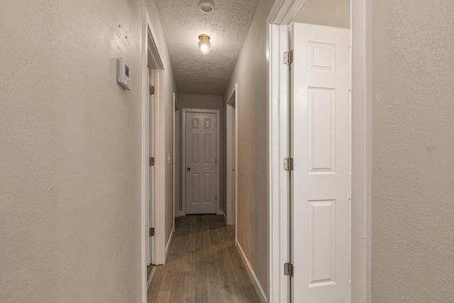 corridor with dark hardwood / wood-style floors and a textured ceiling