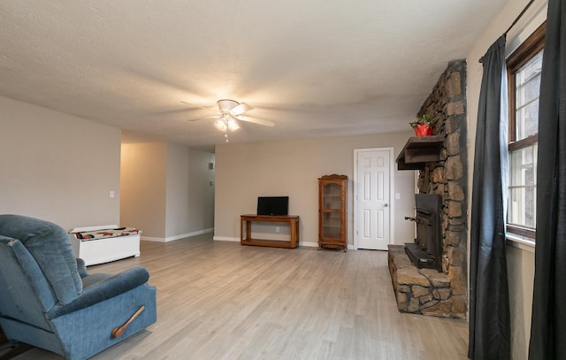 living room with ceiling fan, a textured ceiling, and light hardwood / wood-style floors