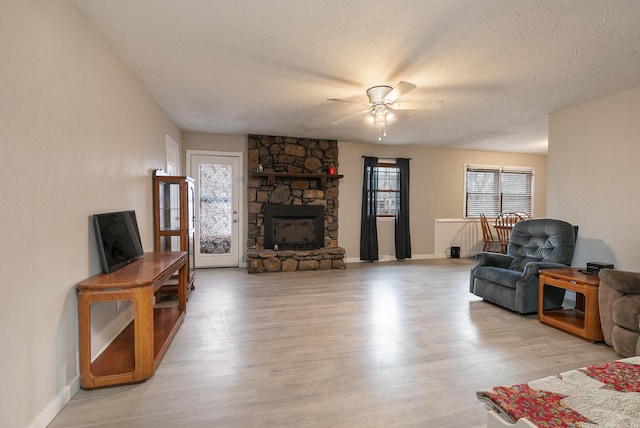 living room featuring a fireplace, a wealth of natural light, light hardwood / wood-style floors, and a textured ceiling