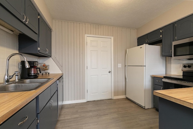 kitchen featuring sink, appliances with stainless steel finishes, backsplash, light hardwood / wood-style floors, and a textured ceiling